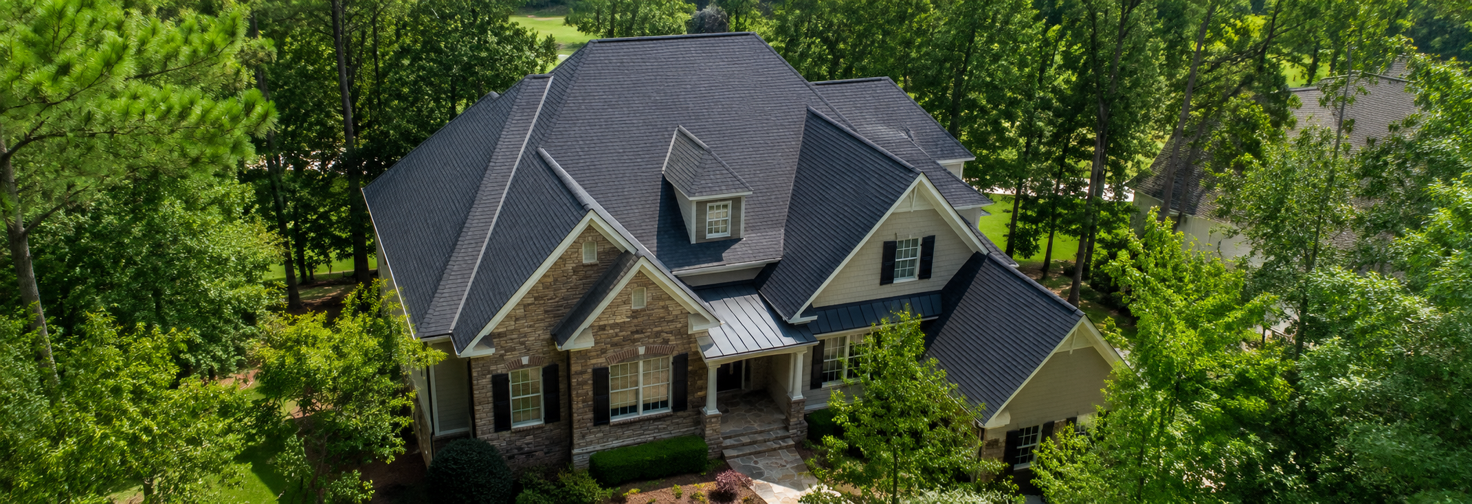 Aerial view of a Peachtree City-area home surrounded by pine and hardwood canopy showing a clean, well-maintained roof