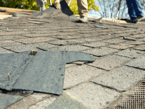 Roofer removing damaged shingles from a roof in Fayetteville, GA during roof replacement.
