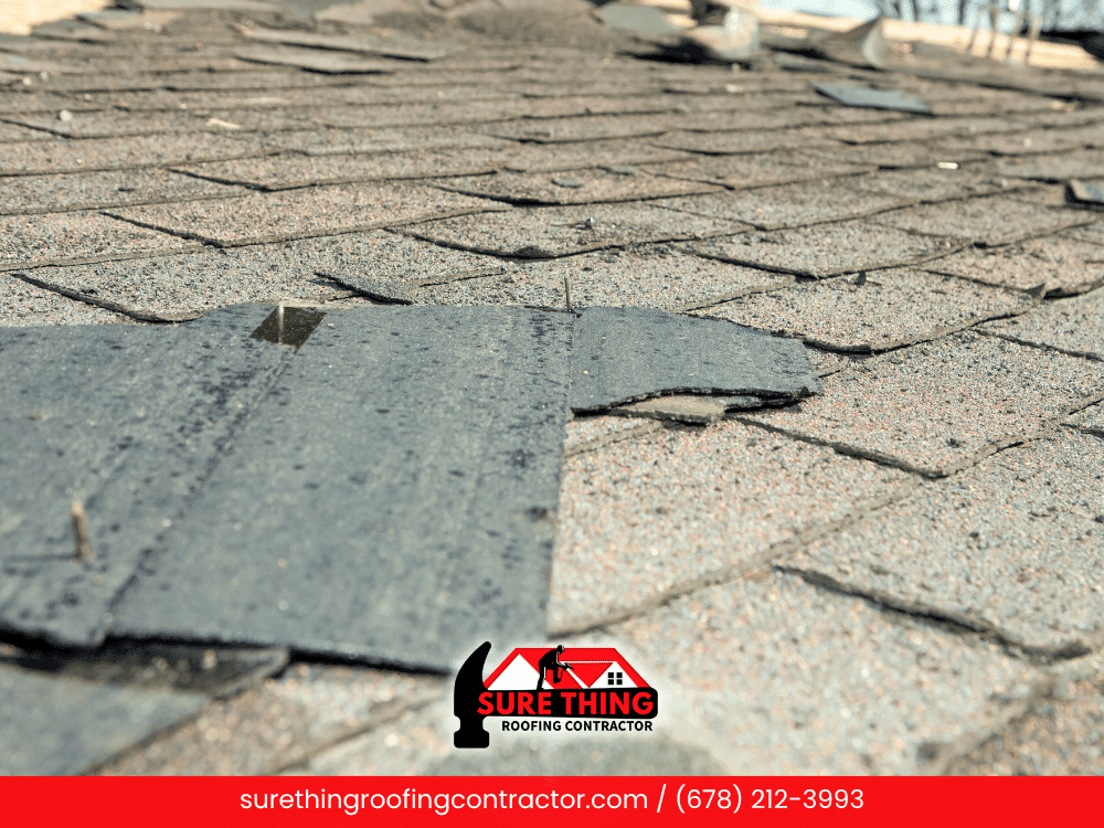Torn roof shingles lifted due to storm damage on a roof in Georgia.